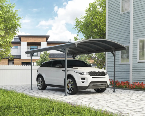 Bil under en carport på en stenlagd uppfart framför ett hus