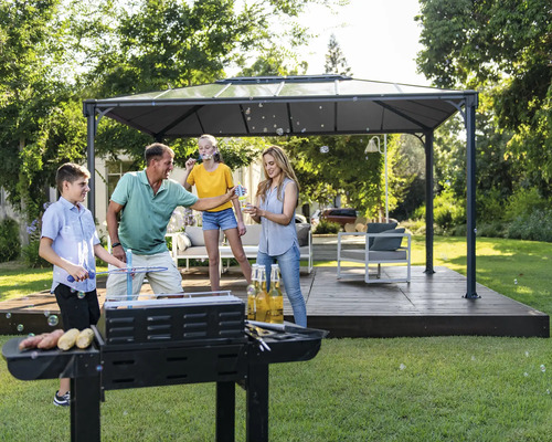 Familjen grillar i trädgården under en paviljong och gör bubblor