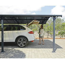 En kvinna står under en carport och öppnar bagageluckan på en bil.