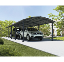 Två bilar parkerade under en carport på en asfalterad uppfart framför ett hus.