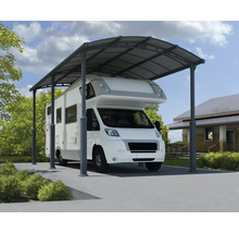 Husbil under en metallcarport på en fastighet.