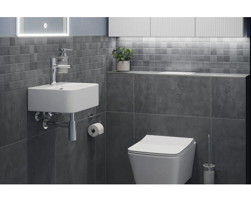 Badrum med handfat, toalett och grå kakel