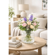 Blombukett med rosor och riddarsporre i en glasvas på ett bord