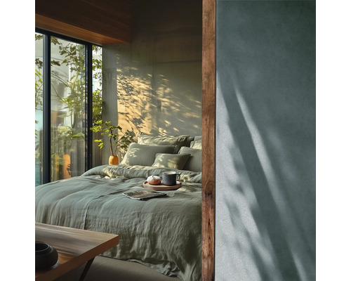 Sovrum med säng, kuddar, täcke och växter bredvid ett fönster