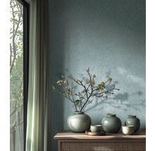 Dekorativ arrangemang med vaser och grenar på en skänk framför en vägg