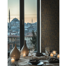 Dekorativt matbord med porslin, glas, ljus och vaser framför ett fönster med utsikt över staden.