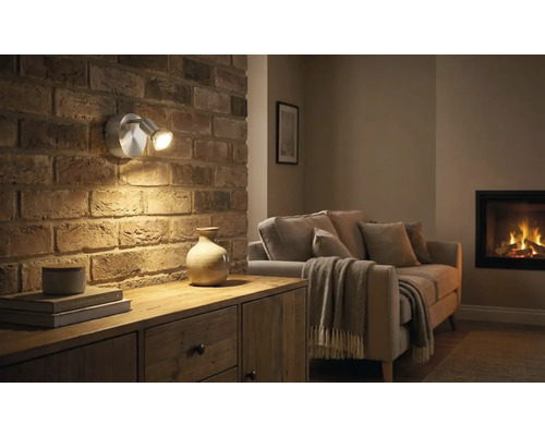 Vardagsrum med tegelvägg, byrå och vägglampa med två lampor