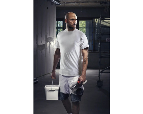 Hantverkare med t-shirt, shorts, hink och murslev på en byggarbetsplats