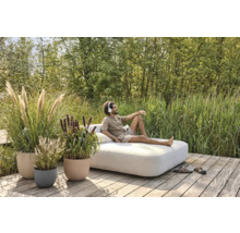 Utomhusscen med en man på en dagsbädd, omgiven av växter i planteringskärl