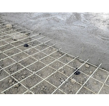 Betonggolv med armeringsnät och distanser före gjutning.