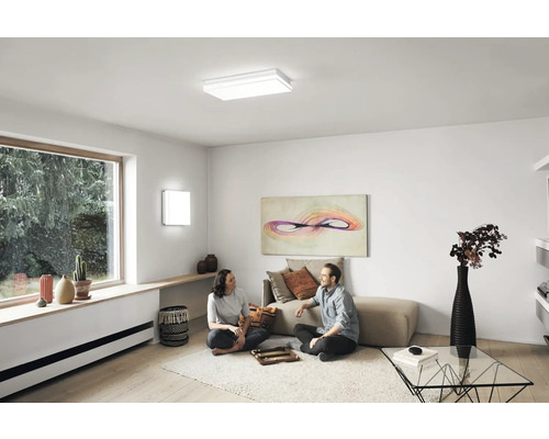 Vardagsrum med infälld taklampa, vägglampa och lekande människor
