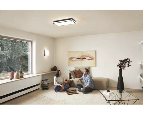 Ljust vardagsrum med taklampa och vägglampa