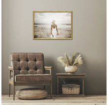 Vardagsrumsinredning med fåtölj, sidobord och inramad strandbild