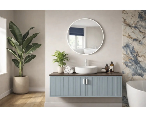 Ljust badrum med tvättställsskåp, rund spegel och krukväxter.