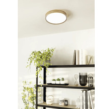 Taklampa med träkant i ett ljust rum ovanför en hylla.