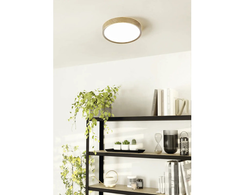 Taklampa med träkant i ett ljust rum ovanför en hylla.