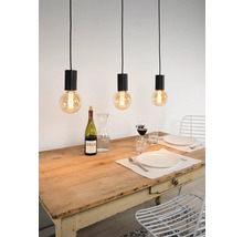 Scen med tre hänglampor över ett matbord med porslin och drycker