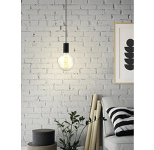 Hänglampa med Edisonglödlampa framför en tegelvägg