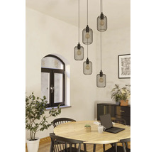 Matsal med träbord, stolar och en taklampa med flera svarta lampskärmar