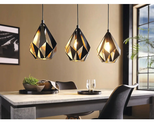 Tre geometriska hänglampor i metall ovanför ett matbord