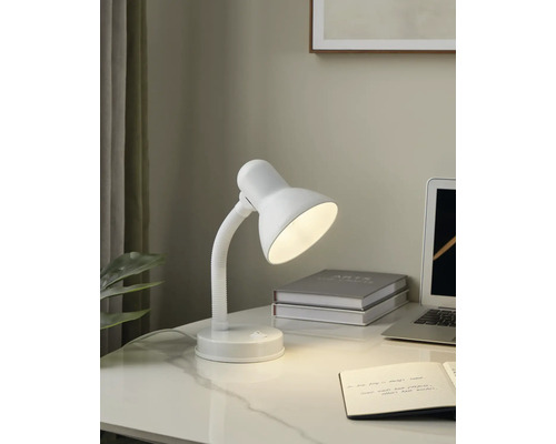 Skrivbordsscen med en vit skrivbordslampa, en anteckningsbok och en bärbar dator