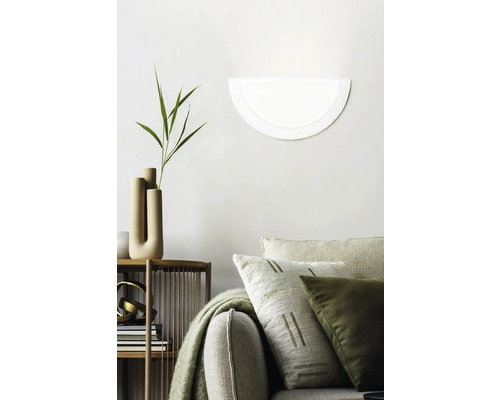 Dekorativt vardagsrum med vägglampa, soffa och hylla