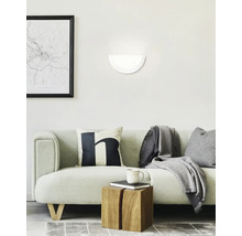 Vardagsrum med soffa, vägglampa och dekorativa föremål för en mysig atmosfär