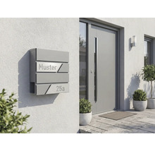 Modern brevlådesystem på en husvägg med inskriptionen Muster 25a