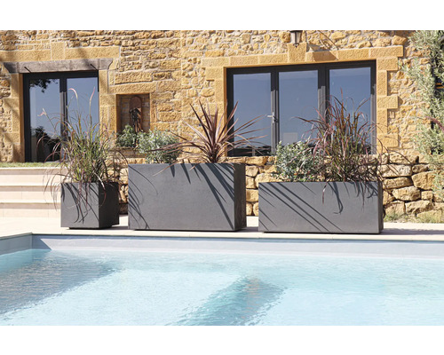 Tre grå planteringskärl i olika storlekar vid poolen