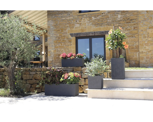 Dekorativa blomkrukor i stengods med blommande växter i en trädgård