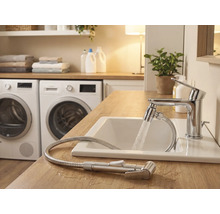 Ljust badrum med handfat, blandare med duschslang och tvättmaskiner