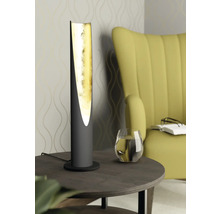 Dekorativ bordslampa med guldfärgad insida på ett sidobord