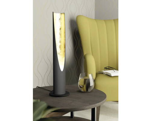 Dekorativ bordslampa med guldfärgad insida på ett sidobord