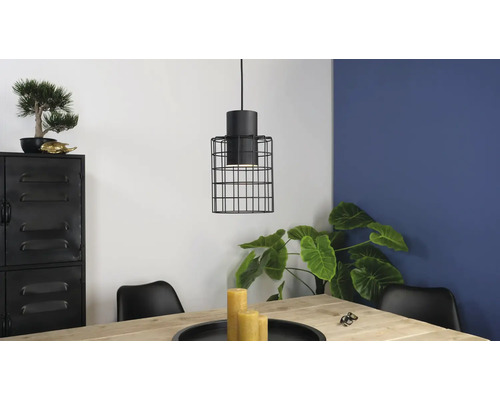 Miljöbild med en hänglampa med skärm i burform ovanför ett träbord