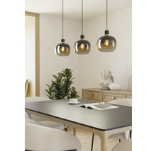 Tre pendellampor med runda glasskärmar över ett matbord.