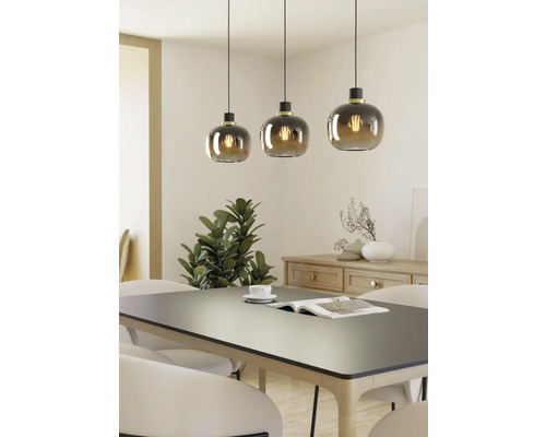 Tre pendellampor med runda glasskärmar över ett matbord.