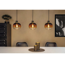 Miljöbild med tre pendellampor i glas ovanför ett matbord