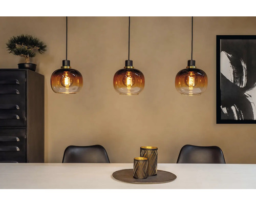 Miljöbild med tre pendellampor i glas ovanför ett matbord