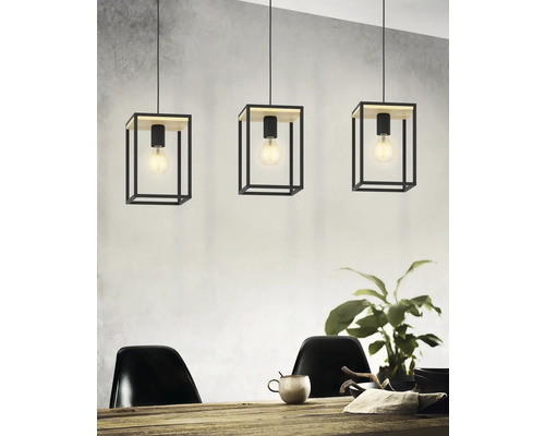 Tre pendellampor med kubiska lampskärmar i metall och träelement ovanför ett matbord.