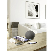 Bild av ett vardagsrum med smarta hemenheter som högtalare, surfplatta, smartphone och glödlampa på ett bord.