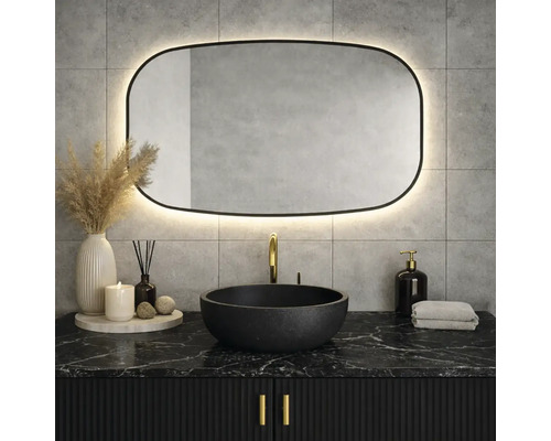 Badrum med svart tvättställsskåp, runt handfat och upplyst spegel