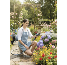 Kvinna vattnar blommor med en trädgårdsspruta i en blomstrande trädgård.