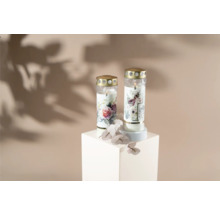 Två gravljus med blommotiv på en vit sockel