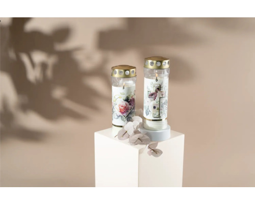 Två gravljus med blommotiv på en vit sockel.