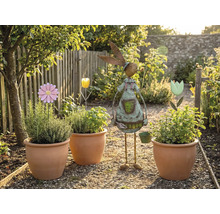 Trädgårdsscen med planterade terrakottakrukor, blomsterstickor och en trädgårdsdekoration i form av en kanin