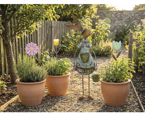Trädgårdsscen med planterade terrakottakrukor, blomsterstickor och en trädgårdsdekoration i form av en kanin