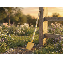 Trädgårdsscen med spade lutad mot trästaket