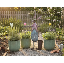 Trädgårdsscen med planterade krukor, metallhare och dekorationer på en grusgång