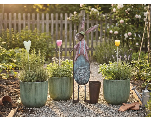 Trädgårdsscen med planterade krukor, metallhare och dekorationer på en grusgång