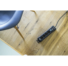 Grenuttag med överspänningsskydd och strömbrytare på trägolv.